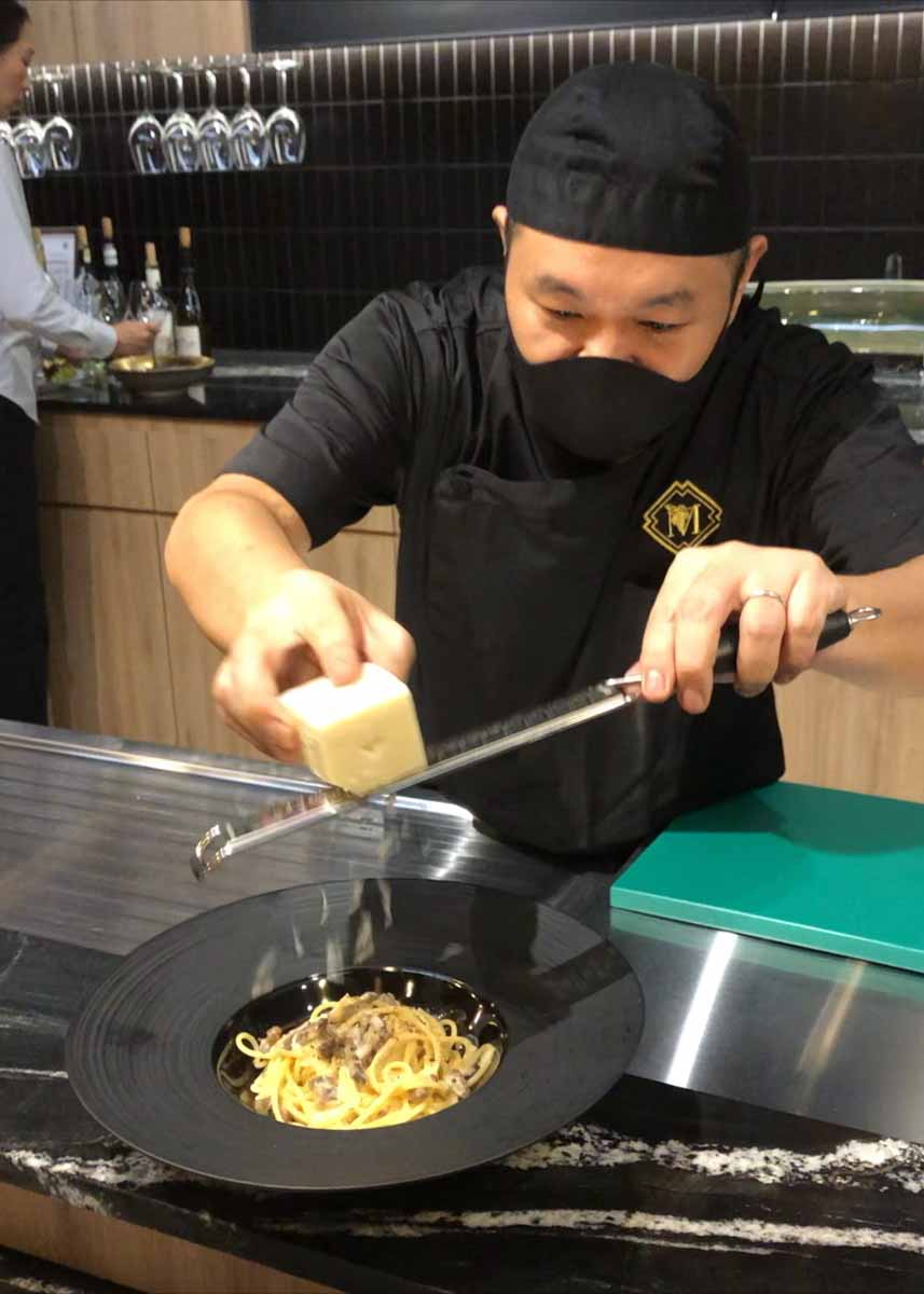 チーズを振りかけるシェフ